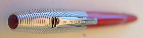 4584: REYNOLDS INTERNATIONAL BALLPOINT IN ANODIZED RED WITH ALUMINUM CAP WITH CIRCUMFERENTIAL GROVES. CAP COVER HAS RED TIP. CAP REMOVES AND SNAPS ON OVER THE FRONT END OF THE PEN. COMES WITH PAPER INSTRUCTIONS AND GUARENTEE. CONTAINS A SLIGHTLY TATERED, BUT CLEAR CELLOPHANE COVER AND AN ALUMINUM PEDISTOOL.. ALL ITEMS FIT INSIDE AND ELABORATE CYLINDRICAL DISPLAY CASE IN DARK BLUE VELEVENTEE WITH REYNOLDS PEN LOGO STILL VISABLE